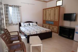 um quarto com uma cama, uma televisão e cadeiras em DIVINEHOMESTAY COMFORT SUITE em Tirupati