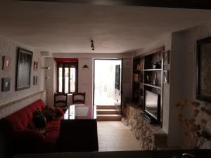 uma sala de estar com um sofá vermelho e uma televisão em La casa de Tento em Tózar
