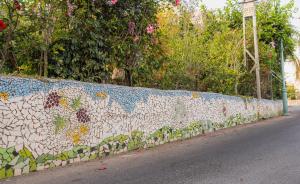a stone wall with flowers on it next to a street at Khalil lane in the Village in Mi‘ilyā