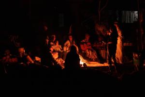 een groep mensen die rond een vuur in het donker zitten bij Espaço Ecológico e Pousada Terra Betania in São João da Aliança