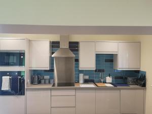 a kitchen with white cabinets and a stove at Arrochoile Cottage in Glasgow