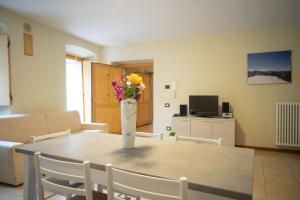 Perarolo Apartments في Perarolo di Cadore: غرفة معيشة مع طاولة مع إناء من الزهور عليها