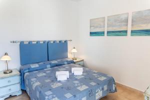 een slaapkamer met een blauw bed en 2 nachtkastjes bij La Joya del Molino. Vistas a la Piscina, 1hab, A/C in Costa Teguise