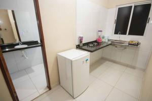 uma pequena cozinha branca com um lavatório e um frigorífico em Flat Bela Vista em Japaratinga