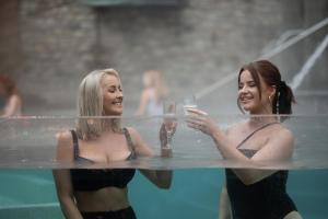 The Rabbit Hotel & Retreat في تيمبلباتريك: سيدتان في حمام سباحة يحملان أكواب من النبيذ