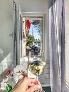 パリにあるロフト 5 プレイシズ ウィズ ビュー オン エッフェル タワーの窓際にワインを持つ者