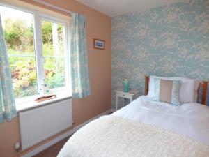 een slaapkamer met een bed en een raam bij Hafod Cottage in Cemaes Bay