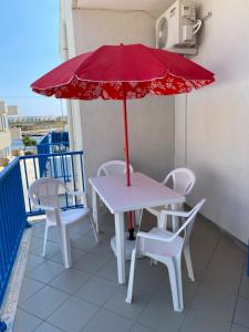 een tafel en stoelen met een rode parasol op een balkon bij casa patrizia in Villanova di Ostuni