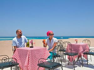 a man and a woman sitting at a table on the beach at Sea View Hotel in Hurghada