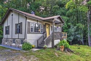 Casa pequeña con porche delantero y puerta amarilla en Shaw Creek Cottage with Fire Pit and Forest Views, en Hendersonville