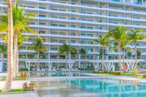 a large apartment building with a swimming pool and palm trees at Garza Blanca Resort & Spa Cancun in Cancún
