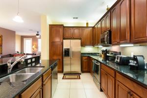 a kitchen with wooden cabinets and a stainless steel refrigerator at 4Br 2Bath Condo Balcony 5min Conv Center 2020ft in Orlando