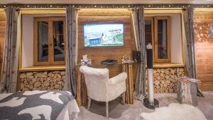 Zimmer mit einem TV, einem Stuhl und einem Tisch in der Unterkunft Le Chalet de l'Atelier - Le Nord in Champéry