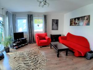 a living room with a red couch and two chairs at Twistesee Ferienwohnung in Bad Arolsen