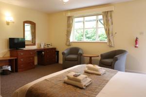 a bedroom with a bed with two towels on it at St George's Lodge, Bisley in Brookwood