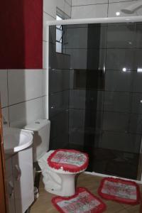 a bathroom with a toilet and a shower with rugs at Residencial Emerencio in Passo de Torres