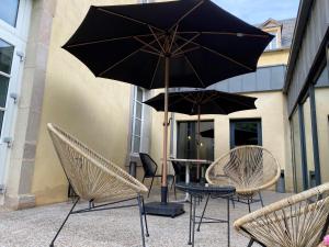 a patio with chairs and a table with an umbrella at Le 1837 in Saint-Affrique