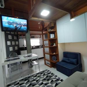 a living room with a table and a tv on the wall at Loft encantador D - 8 km de Floripa in São José