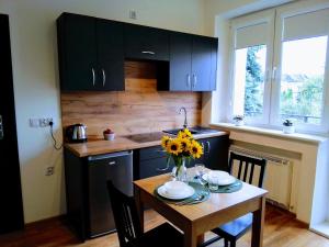 a kitchen with a table with a vase of flowers on it at Orange Apartament in Wadowice