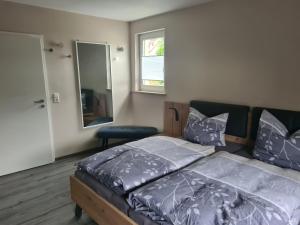 Schlafzimmer mit einem Bett mit blauer Bettwäsche und einem Spiegel in der Unterkunft Pension Im Wiesengrund Steinau Marborn in Steinau an der Straße