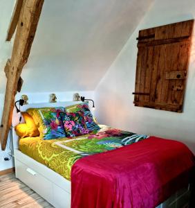 a bedroom with a bed with colorful sheets and a window at La Manch'hôtes in Domjean