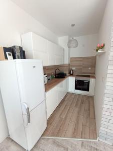 cocina con armarios blancos y nevera blanca en Apartament na Kruczej, en Lubin