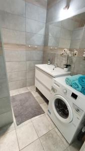 y baño con lavadora y lavamanos. en Apartament na Kruczej en Lubin