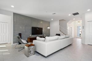 uma sala de estar branca com um sofá branco e uma televisão em 5Br 5Bath Pvt Home BBQ Pool 15min Disney 3056ft em Kissimmee