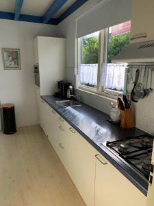 een keuken met witte kasten, een wastafel en een raam bij Kustverhuur, Park Schoneveld, Zeester 68 in Breskens