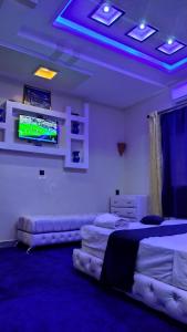 a bedroom with two beds and a tv on the wall at Dar Calme Chez El Bouhali in Skoura