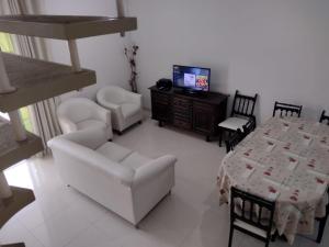 ein Wohnzimmer mit einem Tisch, Stühlen und einem TV in der Unterkunft Vila da Praia in Florianópolis