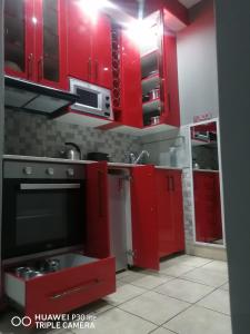 a red kitchen with red cabinets and a stove at The Penthouse in Port Edward
