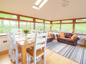 a dining room with a table and chairs and a couch at Tyn Llwyn in Llangollen