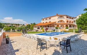 een resort met een zwembad en stoelen en een gebouw bij Villa Natalija in Medulin