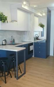 a kitchen with blue and white cabinets and a table at Apartament Dobra Fala in Gdańsk
