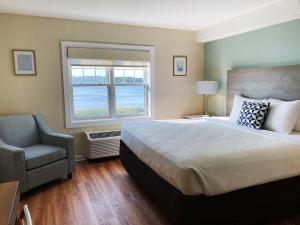 a bedroom with a bed and a chair and a window at Atlantic Beach Hotel Newport in Middletown