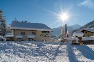 a building covered in snow with the sun in the background at Hotel Pension Wilma in Schruns