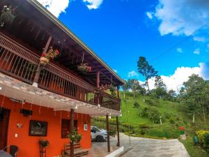 una casa roja con una colina verde en el fondo en Hotel Orillas del Pizano, en Jardín