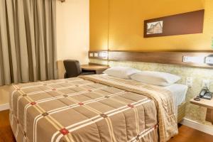 a hotel room with a bed and a desk at Hotel 10 São Leopoldo in São Leopoldo