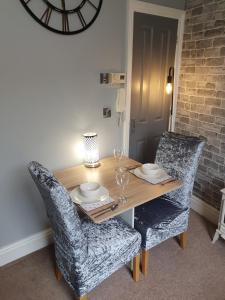 a dining room table with two chairs and a clock at Central Matlock Apartment in Matlock