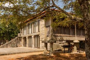 Casa da Eira - Alojamento Local في براغا: مبنى حجري امامه شجرة