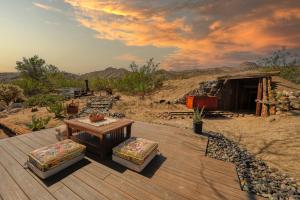 a wooden deck with a table and chairs and a building at @ Marbella Lane - The Wine Mine Desert Escape in Joshua Tree