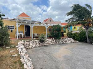 a yellow house with a stone wall at La Bamba in Willemstad