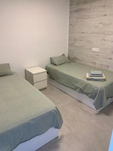 a bedroom with two beds and a white wall at Apartamento Salou Playa Jaime I in Salou