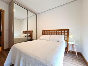 a bedroom with a large white bed and a mirror at Apartamento Prime Master Collection in Passo Fundo