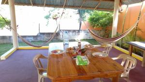 een houten tafel met stoelen en een hangmat op een veranda bij Conrado's Guesthouse B&B in Las Avispas