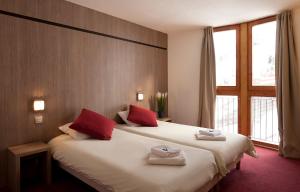 una habitación de hotel con una cama grande con almohadas rojas en Hôtel Club mmv Les Mélèzes **** en Arc 2000