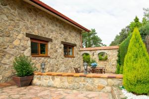 uma casa de pedra com um banco à frente em La Casita de las Hortensias em Ortigosa del Monte