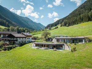 a house on a hill with a green field at Innermoser Bauernhof - Chalets in Molini di Tures