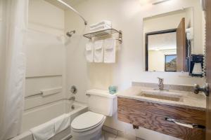 a bathroom with a toilet and a sink and a tub at Americas Best Value Inn & Suites Harrisonville in Harrisonville